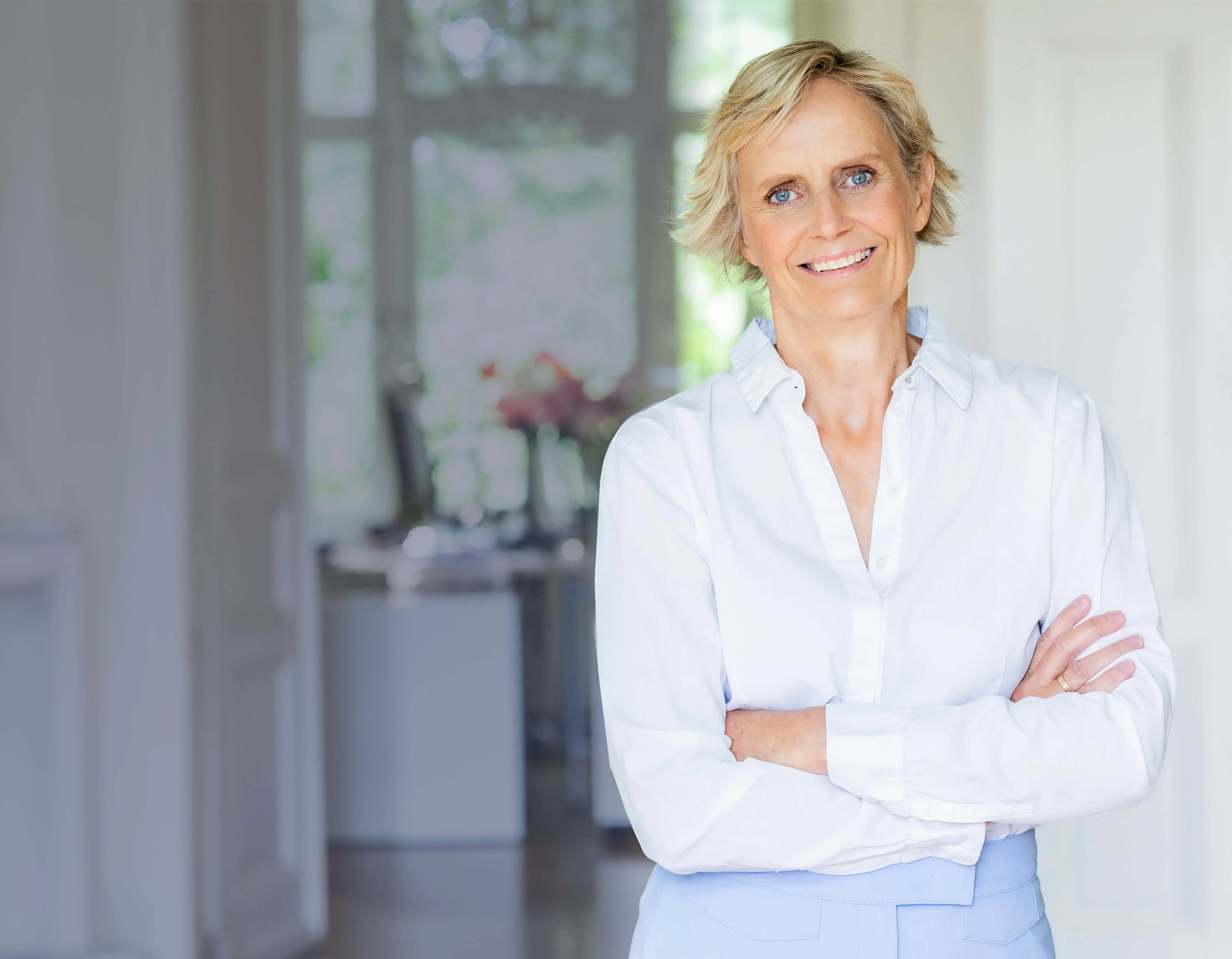 Christina Janssen mit verschränkten Armen in einem hellen Raum